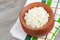 Homemade crumbly farmer\\\'s cheese in a clay pot. Wooden background. Copy space, top view