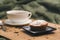 Homemade cupcake with powdered sugar on a black plate and a white cup of tea with natural additives on a wooden tray