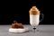 Homemade Dalgona coffee in a transparent glass cup with ingredients on dark background. Recipe popular Korean drink latte with
