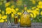 Homemade dandelion flowers tincture in glass bottle on a wooden table in a summer garden, closeup