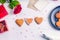 Homemade decorating cookies in shape of heart as gift for lover on Valentine`s day. White wooden table with greeting card, rose a