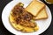 Homemade Denver Omelette on a white plate on a black background, side view