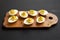 Homemade Deviled Eggs with Chives on a rustic wooden board on a black background, side view