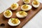 Homemade Deviled Eggs with Chives on a rustic wooden board on a white wooden background, low angle view. Close-up