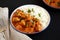Homemade Easy Indian Butter Chicken with Rice on a Plate on a black background, side view