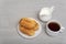 Homemade eclairs, coffee and milk. Traditional French eclairs. Profiteroles on saucer. Gray background