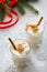 Homemade Eggnog Christmas milkshake with cinnamon, served in two cups on a stone or slate background, decorative ornaments,