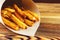 Homemade fast food portion of french fries in paper bag on wood table