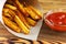 Homemade fast food portion of french fries in paper bag on wood table