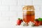 Homemade fermented kombucha in a glass jar and fresh apples on a background of a white brick wall. A healthy probiotic