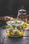 Homemade feta cheese cubes in jar with olives oil and herbs on dark rustic table background.  Marinated feta cheese. Tasty food.