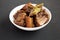 Homemade Filipino Adobo Pork in a white bowl on a black background, side view. Close-up