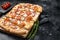 Homemade Flammkuchen or tarte flambee with cream cheese, bacon, tomato and onions. Black background. Top view. Copy