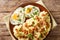 Homemade food mashed potatoes with bacon and parsley served with fried eggs closeup on a plate. Horizontal top view