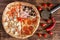 Homemade four-piece pizza with pepperoni, salami, red chili pepper, ham, mushrooms, cheese, tomatoes lies on a natural wooden