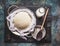 Homemade fresh cheese in dish and cheesecloth with milk and wooden spoon on rustic background