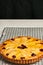 Homemade, freshly baked pear cranberry tart with almonds cooling on a wire cooling rack