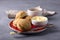 Homemade freshly baked scones with cheese and herbs on a red plate with butter, a cup of coffee on a gray textured background