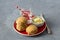 Homemade freshly baked scones with cheese and herbs on a red plate with butter on a gray textured background