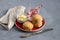 Homemade freshly baked scones with cheese and herbs on a red plate with butter on a gray textured background