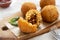 Homemade fried Arancini with basil and Marinara on a white wooden table, side view. Italian rice balls. Close-up