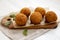 Homemade fried Arancini with basil on a white wooden surface, side view. Italian rice balls. Close-up