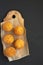 Homemade fried Arancini on a rustic wooden board on a black surface, top view. Italian rice balls. Flat lay, from above, overhead