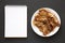 Homemade Fried Bacon on a white plate, blank notepad on a black background, top view. Overhead, from above, flat lay. Copy space