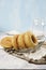 Homemade fried donuts or cronuts in stack with sugar standing on crumpled paper over white wooden concrete table, leaving space