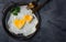 Homemade fried egg in a vintage pan a grey background. Heart-shaped yolk.