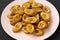 Homemade fried plantains on a pink plate on a black backgound, low angle view. Closeup