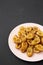 Homemade fried plantains on a pink plate on a black background, low angle view. Copy space