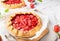 Homemade galettes with strawberries on white marble background