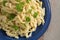 Homemade German egg noodles with cheese, called kaes spaetzle, served with parsley garnish on a blue plate and a rustic wooden