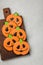 Homemade ginger cookies in the shape of pumpkins for Halloween. On the lighter concrete background. Top view