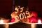 Homemade gingerbread star covered with white icing and letters PF 2019 leaning againts fruits with two candles