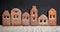 Homemade gingerbread town standing in row sprinkled with powdered sugar on black background