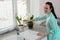 Homemade girl watering flowers in pots in the kitchen