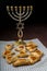 Homemade gomentashi cookies for the Jewish holiday of Purim on a checkered napkin next to the menorah.