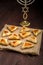 Homemade gomentashi cookies for the Purim holiday on a linen tablecloth next to the menorah.