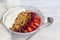 Homemade granola with strawberry chunks in a light plate and yogurt in a jar. On a light background. Vegetarian dish. Healthy