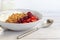 Homemade granola with strawberry chunks in a light plate and yogurt in a jar. On a light background. Vegetarian dish. Healthy