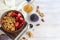 Homemade granola with strawberry chunks in a light plate and yogurt in a jar. On a light background. Vegetarian dish. Healthy