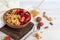 Homemade granola with strawberry chunks in a light plate and yogurt in a jar. On a light background. Vegetarian dish. Healthy