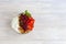 Homemade granola with strawberry chunks in a light plate and yogurt in a jar. On a light background. Vegetarian dish. Healthy