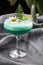 Homemade green cocktail with whey, white egg on grey background. Close up of green cocktail in a glass of margaritas. Vertical