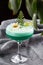 Homemade green cocktail with whey, white egg on grey background. Close up of green cocktail in a glass of margaritas. Vertical