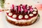 Homemade happy birthday cake with letter candles with chocolade sprinkles and cream spots, shot right on a decorated white glas