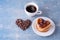 Homemade heart shaped pancakes with berry jam, heart lined with coffee beans and a white cup of hot coffee