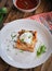 Homemade lasagna with sour cream and fresh chives on wooden background